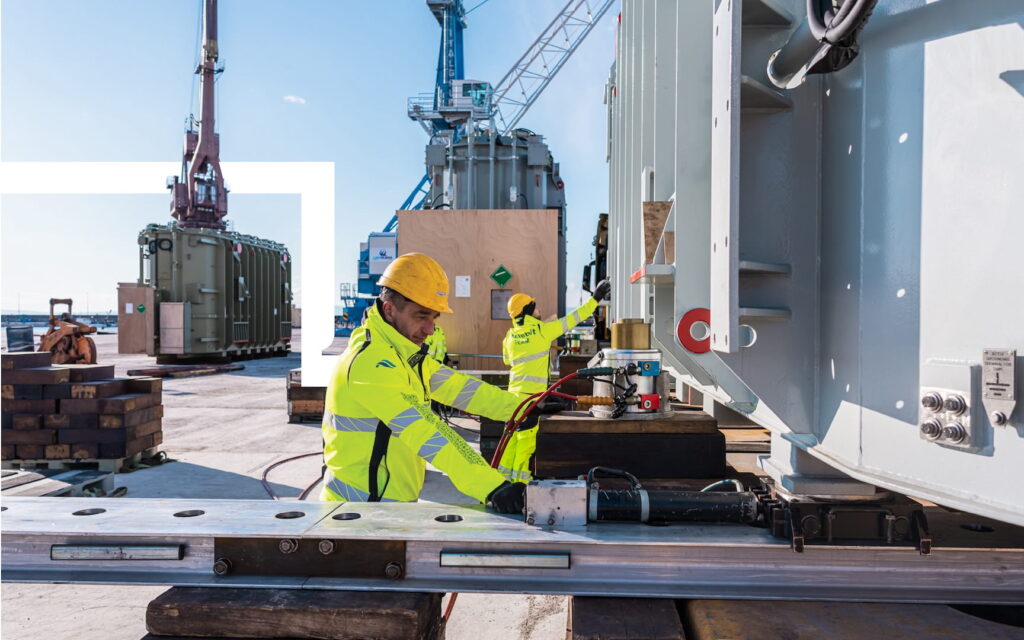 Workers preparing heavy lift cargo with lashing and securing equipment at port