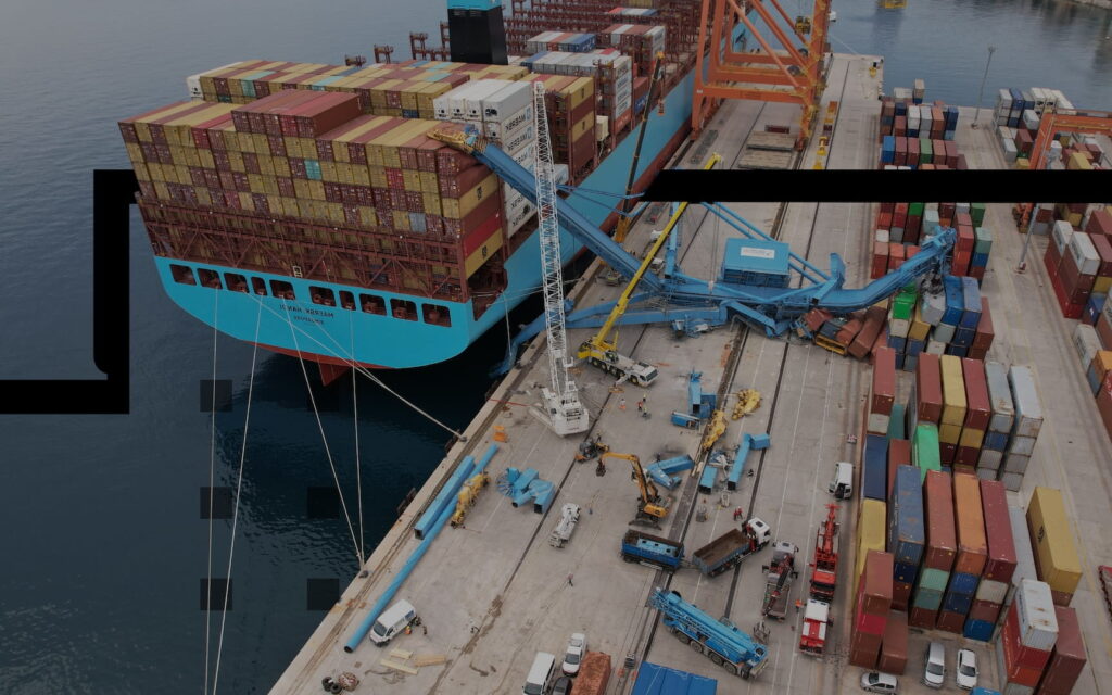Industrial equipment being handled by cranes at a cargo terminal